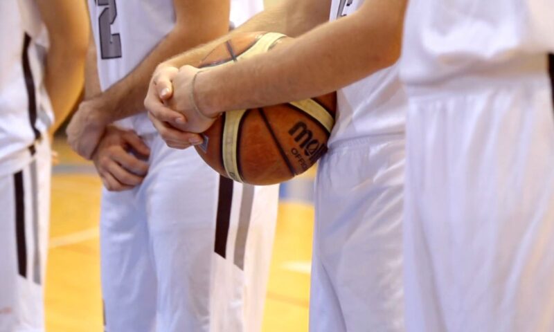 tri momka iz košarkaškog tima stoje u belo crnim dresovima na terenu i jedan od njih drži loptu u ruci