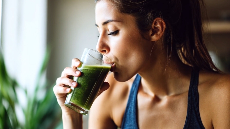 Žena pije zeleni sok za detoks organizma